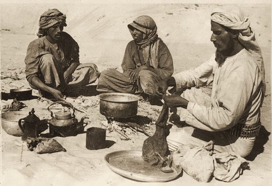 Three men preparing a meal and coffee on the sand